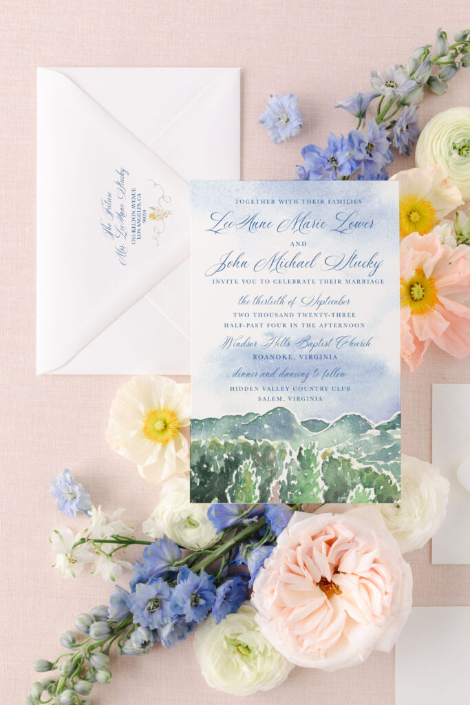 wedding invitation with watercolor mountains on a pink background