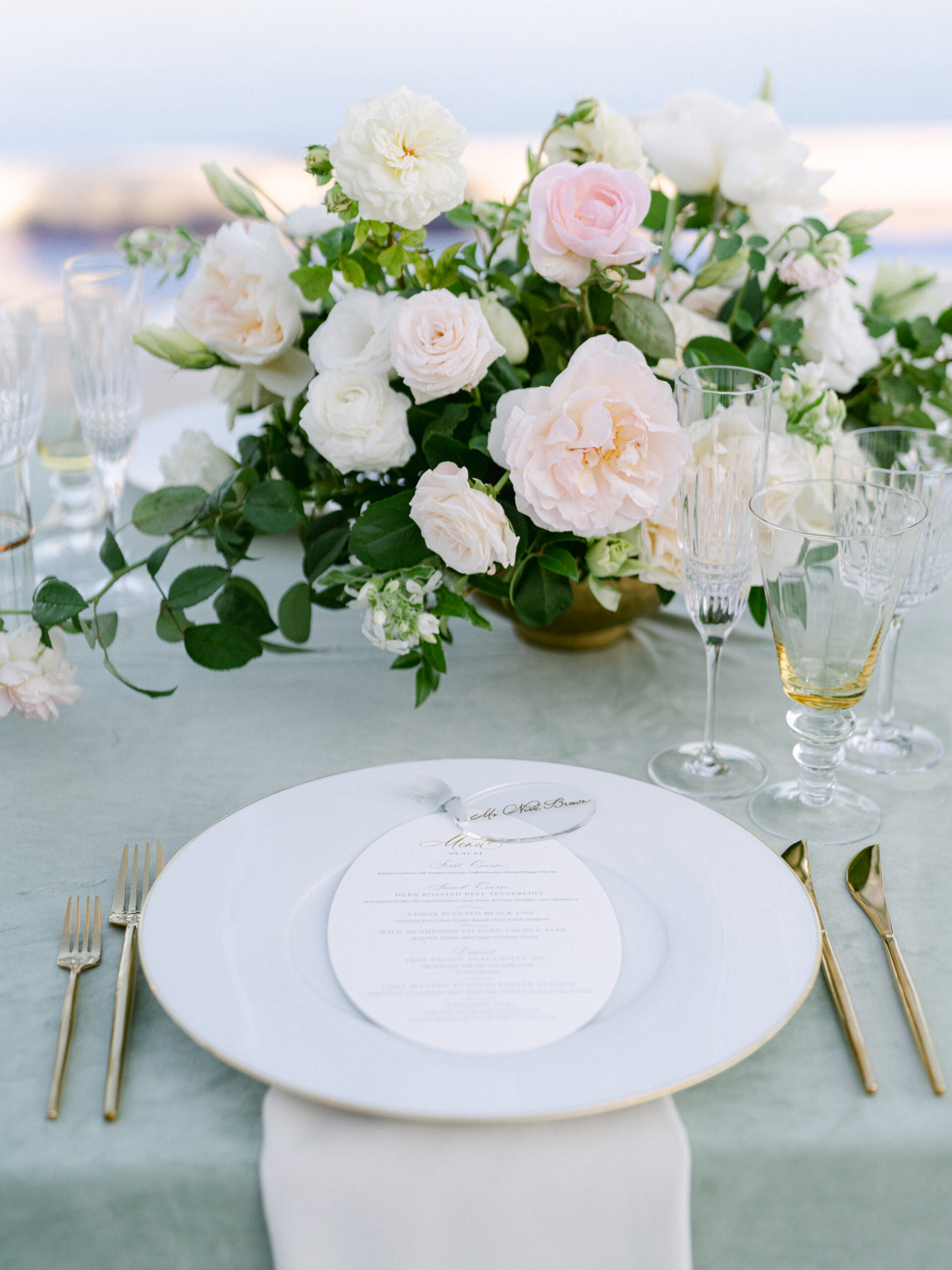 oval menu and acrylic place card on a green table with blush flowers