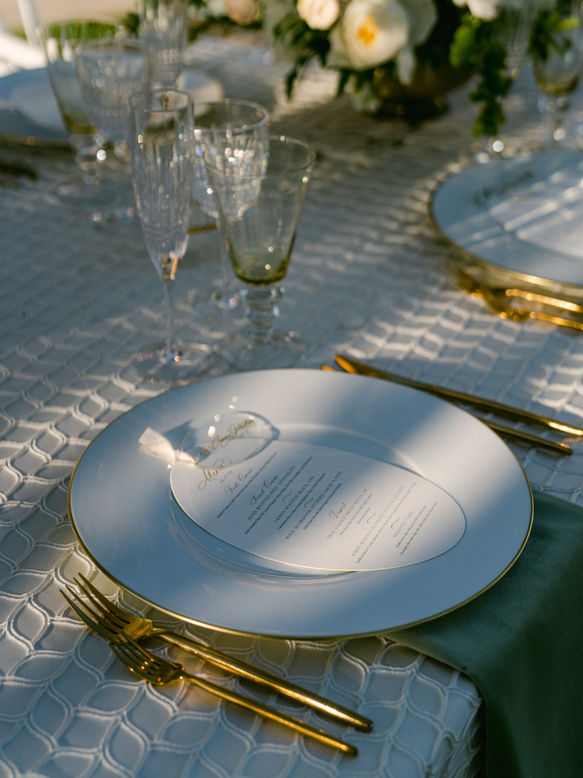 oval menu and acrylic place card on a green table at sunset