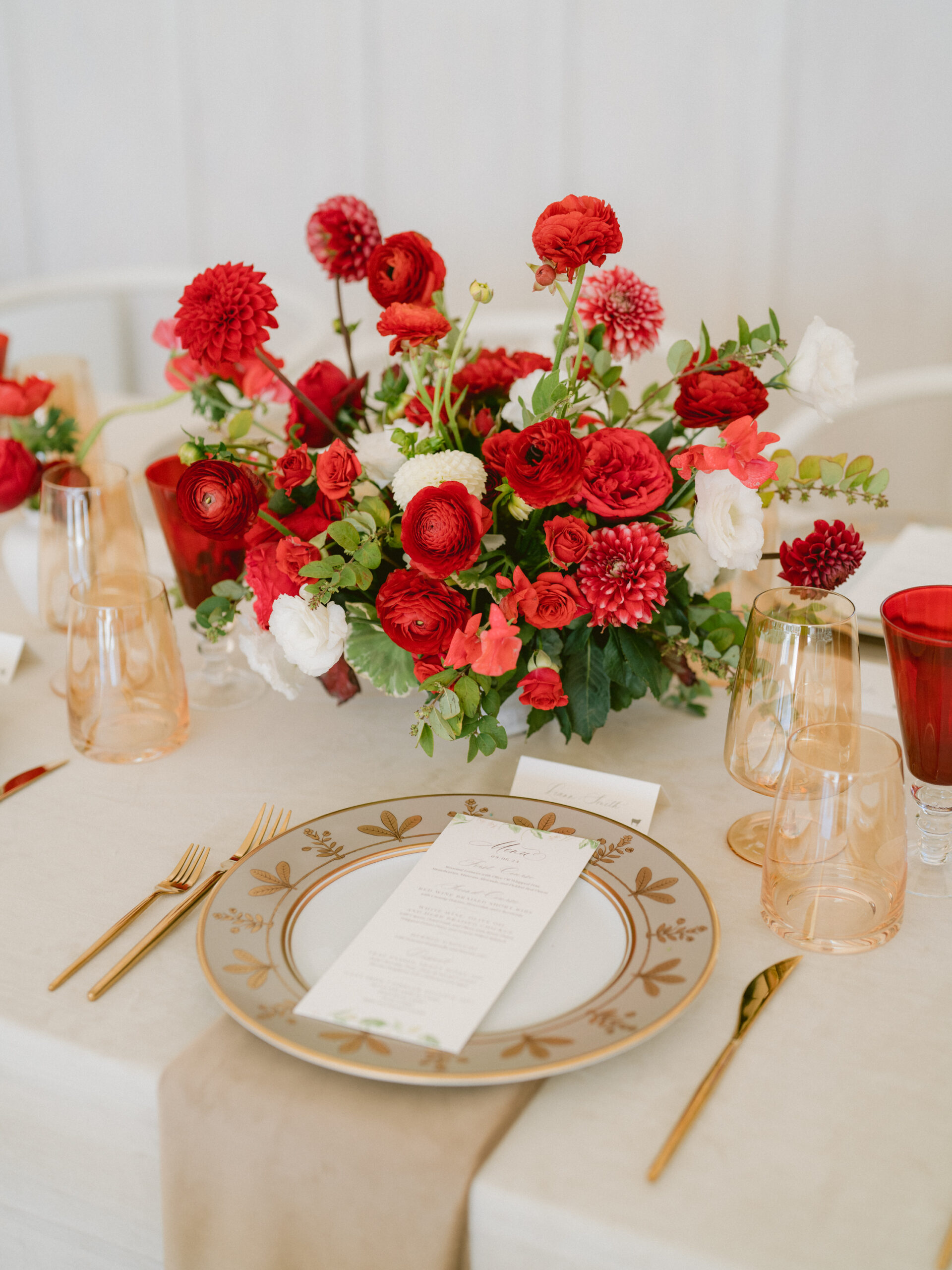 wedding menu and place card on a gold plate with red flowers