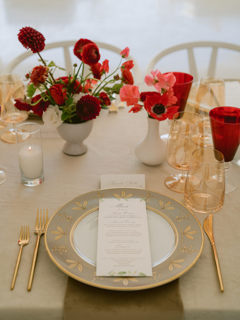 wedding menu and place card on a gold plate with red flowers